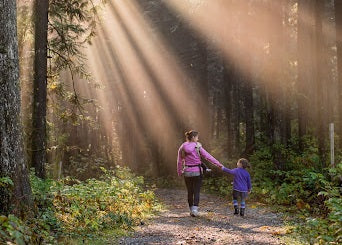 Mother and daughter walking in the forest holding hands 