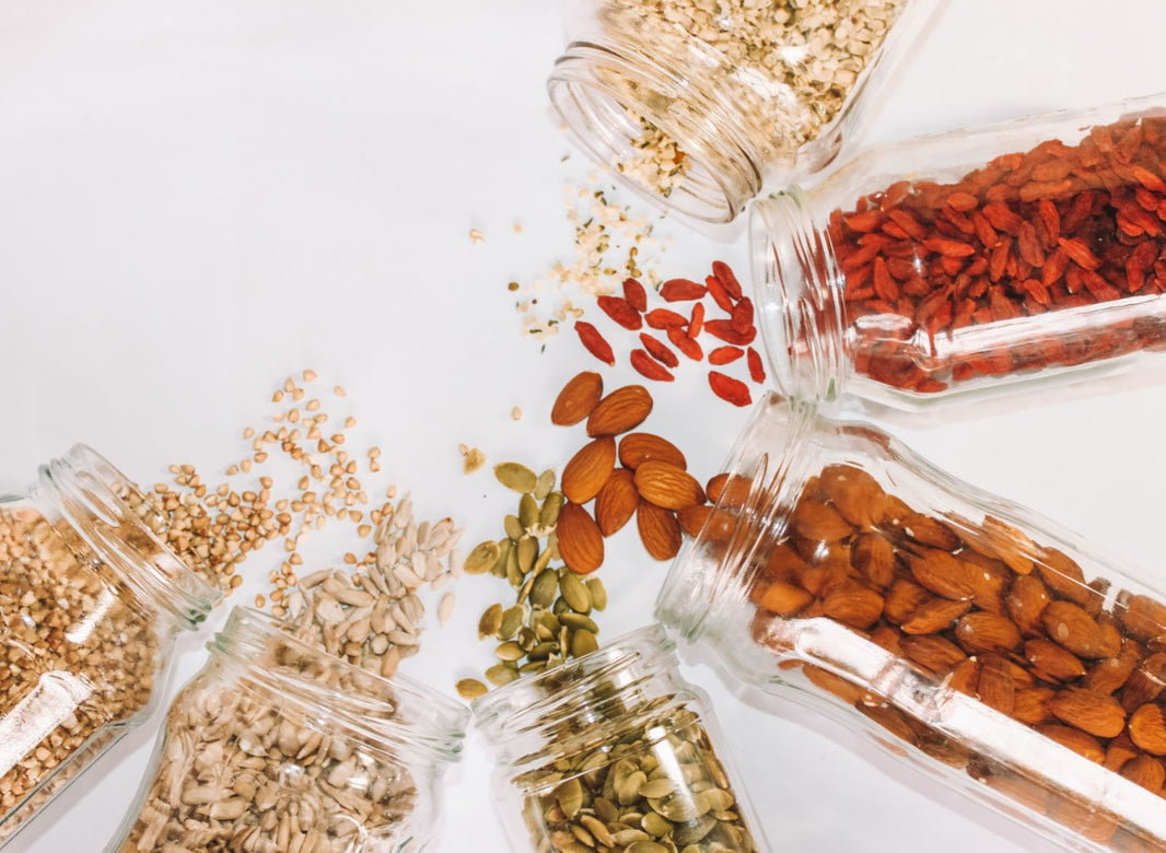 Various nuts and seeds falling out of a glass jar.